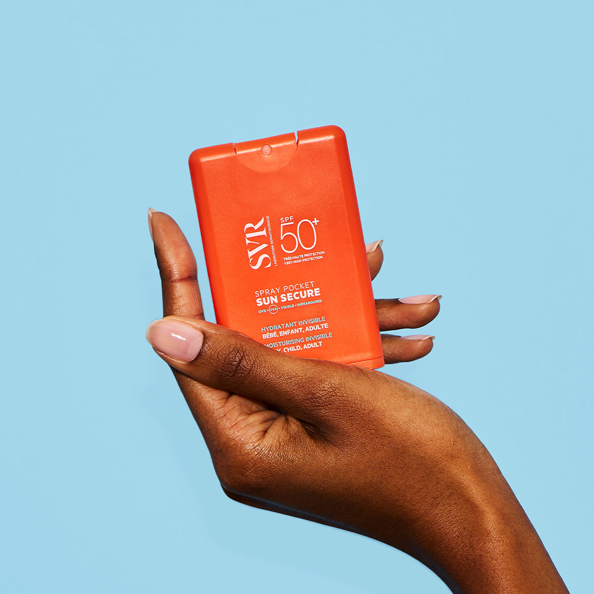 Spray solar SVR Sun Secure SPF50+ într-un recipient portabil portocaliu, ținut în mână pe un fundal albastru deschis.