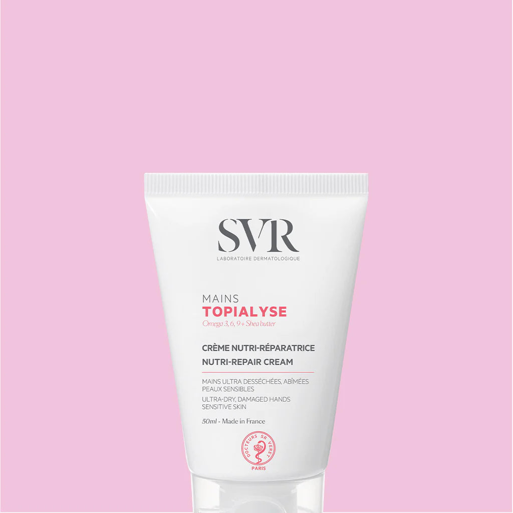 Tub alb de cremă SVR Topialyse Mains de 50ml pentru mâini uscate, cu text negru și roz pe fundal roz deschis.