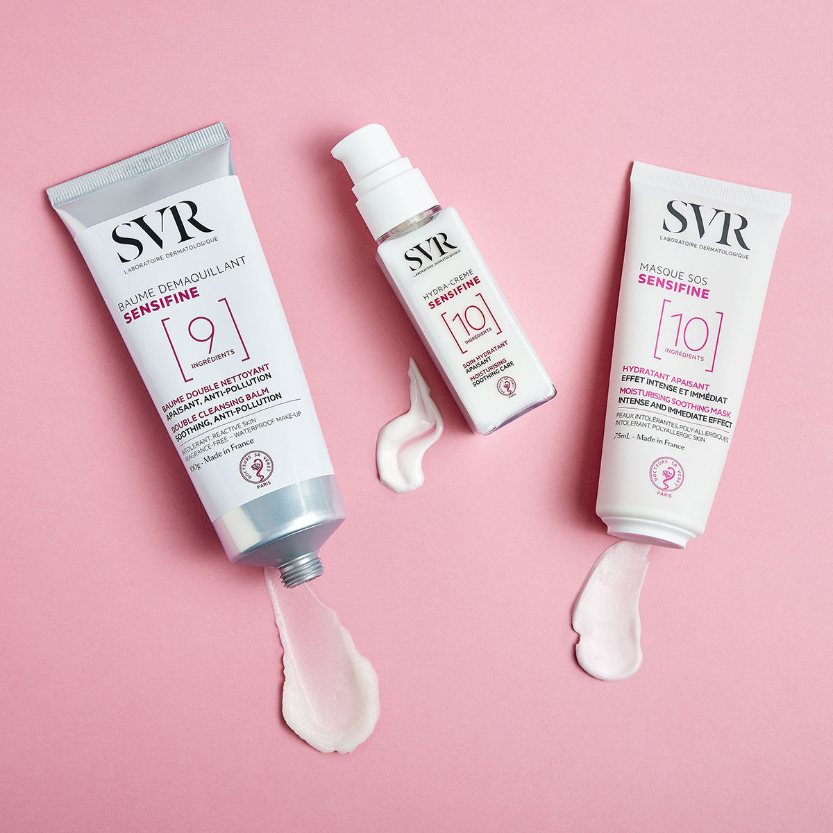 Trei produse SVR Sensifine pentru îngrijirea pielii sensibile, cu texturi cremoase, dispuse pe un fundal roz pastel.