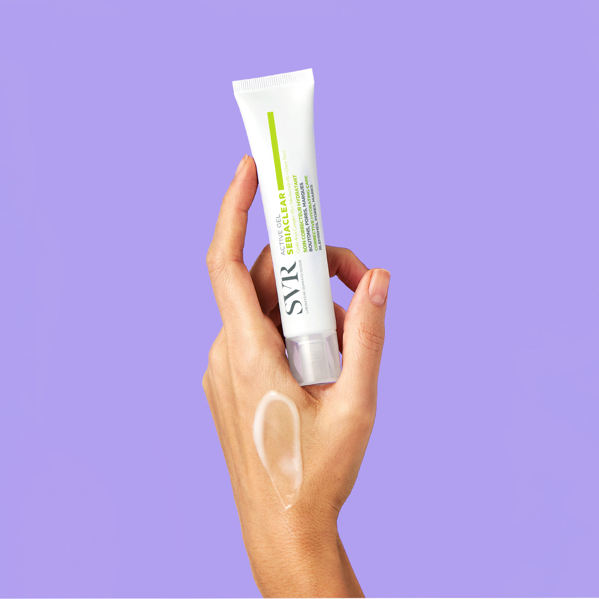 Hand holding a white SVR Sebiaclear Active Gel tube against a purple background with a dab of cream on the skin.