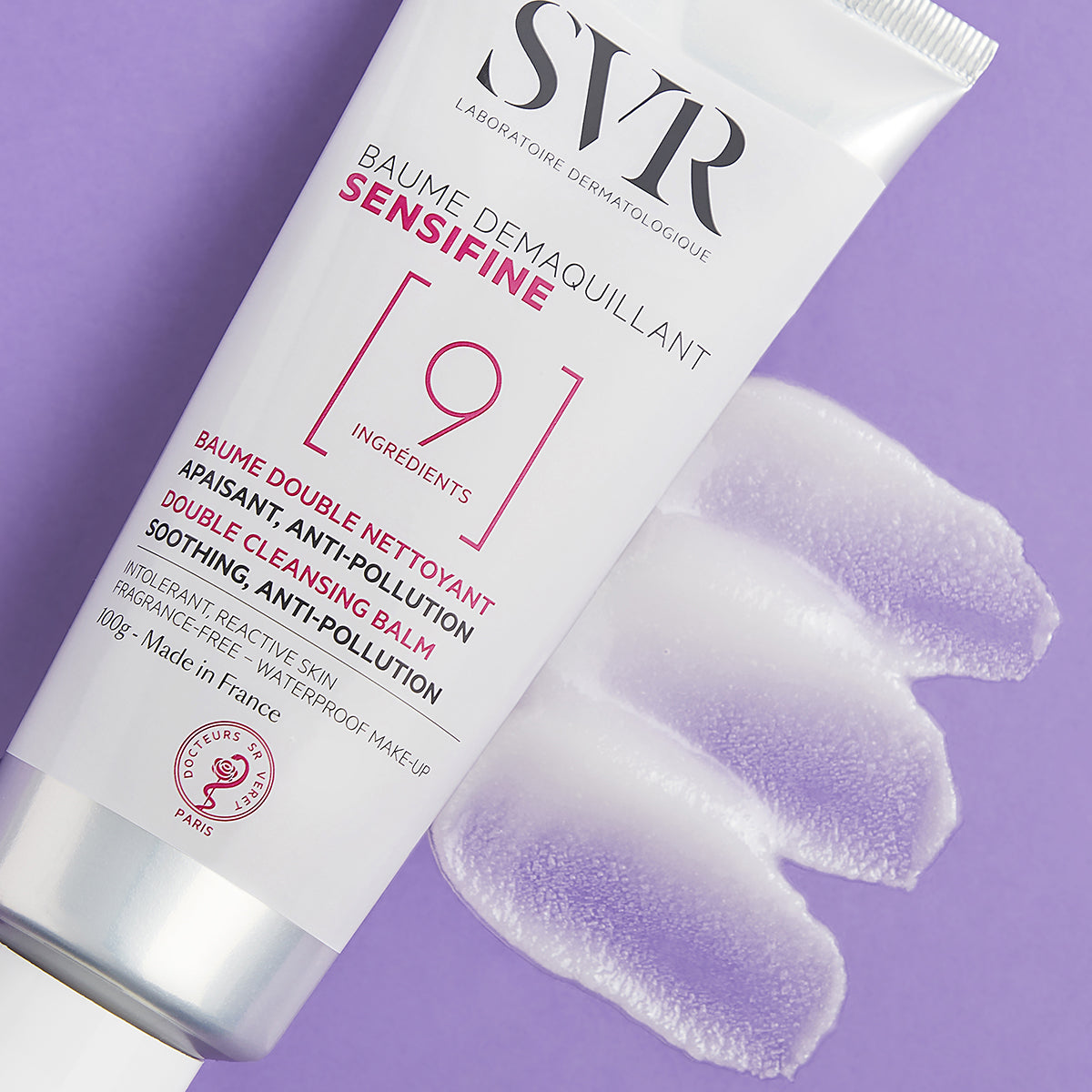 Tub alb de balsam demachiant SVR Sensifine 100g cu textură cremoasă aplicată pe un fundal mov.