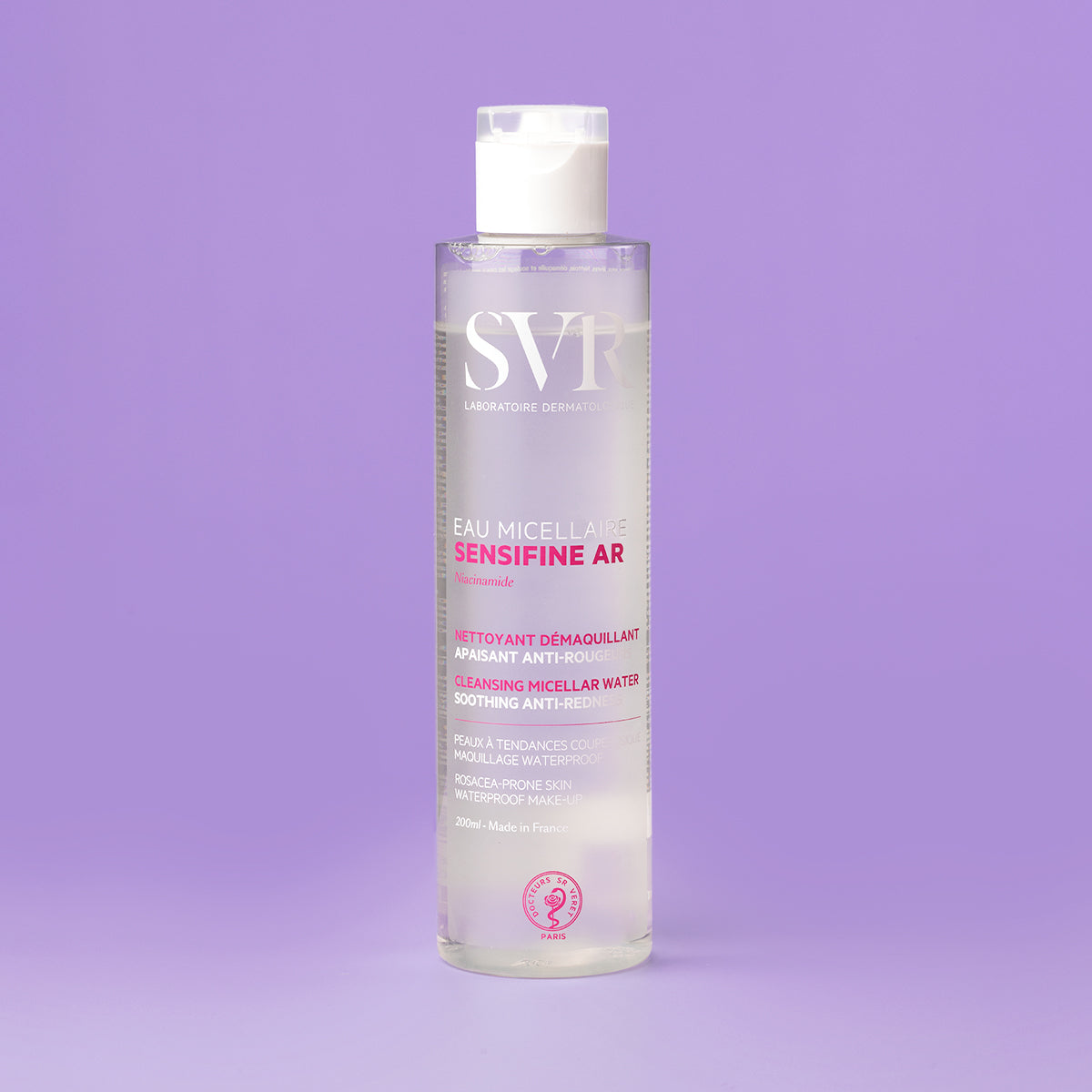 Flacon transparent de apă micelară SVR Sensifine AR de 200 ml, cu capac alb, pe fundal mov, pentru ten cu roșeață.